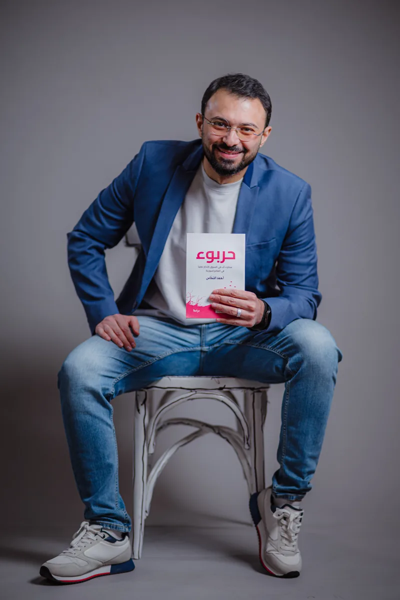 أحمد النحاس جالساً حاملاً كتاب حربوء