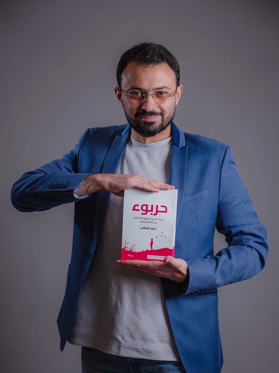 أحمد النحاس واقفاً يحمل كتاب حربوء